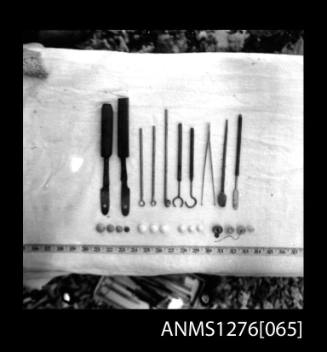 Different shaped metal tools, with a tape measure for scale purposes, on Pearl Island