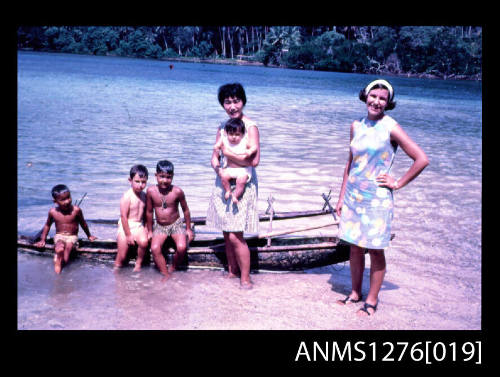 35mm colour transparency of Yurie (or Yulie) George and her three sons, with a woman and another child, with the children sitting on a canoe in shallow water