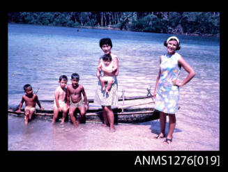 35mm colour transparency of Yurie (or Yulie) George and her three sons, with a woman and another child, with the children sitting on a canoe in shallow water