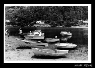 Tidal mooring area with power boats including YWSSN, JT96N and F144N beached or floating in shallow water