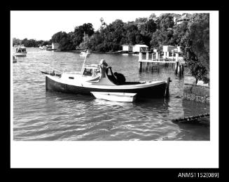 Print depicting imageof MYOPPO half cabin motor boat of timber construction and in-board engine with small dinghy alongside