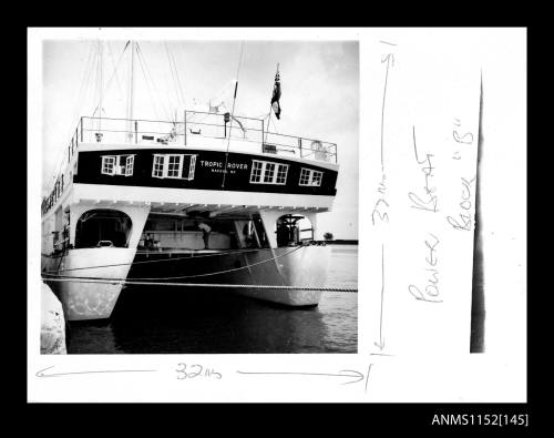 Print depicting large catamaran TROPIC ROVER moored alongside wharf