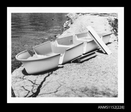 The four hull sections of an open boat laid out on grassed area bow and port side view