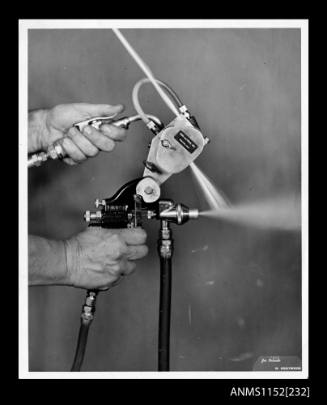 The two-hand held spray guns coupled together for application of fibre glass