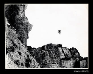 Hang glider flying above cliffs