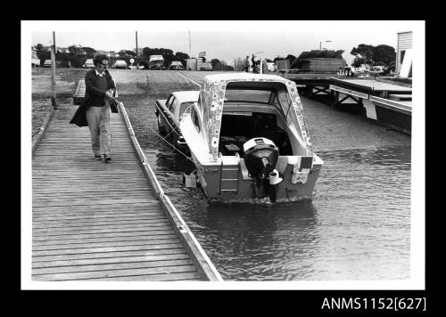 The motor car with boat trailer and boat reversing down a boat ramp