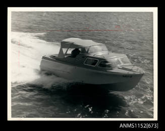 A triple hull half cabin power boat with canvas canopy