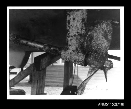 The stern of a boat on a cradle with close up view of one of its propellers and shaft - covered with marine growth to moderate degree