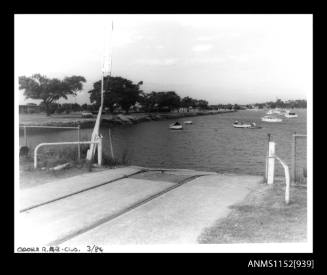 The image in foreground of concrete road and boat ramp with train lines at centreL