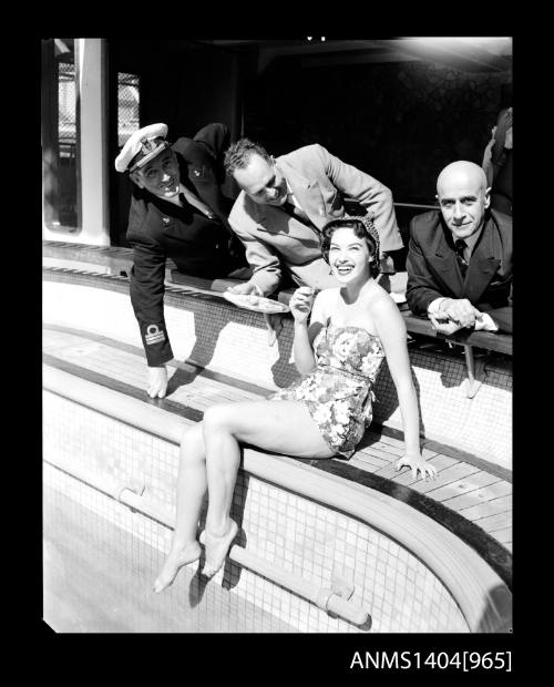 Photographic negative of a swimsuit model posing by a pool on a ship with three men