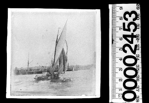 A cutter on Sydney Harbour, New South Wales, with a warship visible in the background