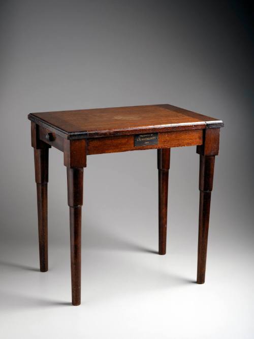 Table top made from lid of Flag Locker off the Bridge of HMAS SYDNEY.  Leg Timber from the HMAS ENCOUNTER, February 1934