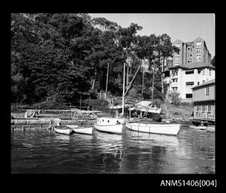 Moored boats, a sandstone retaining wall and several apartment buildings possibly Sydney Harbour