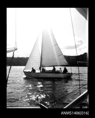 Negative depicting a yacht underway on a river with five passengers