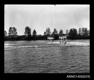 Negative depicting a water-ski event on a river, with eight water-skiers holding flags