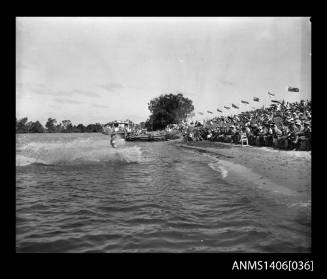 Negative depicting a water-skier in the water, entertaining the crowd on the river bank