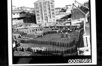 Wharf labourers unloading and stacking cargo of drums from steamship