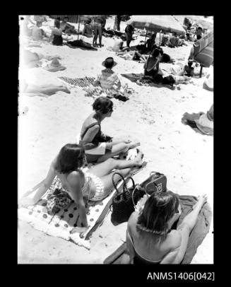 Negative depicting three women at the beach in their swimsuits and wearing sunglasses