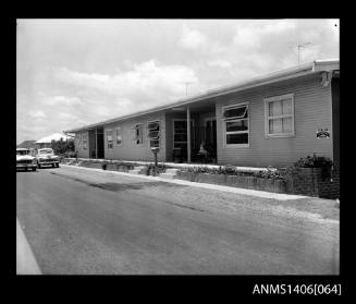 Negative depicting a row of holiday rental town houses and two cars on the road out the front