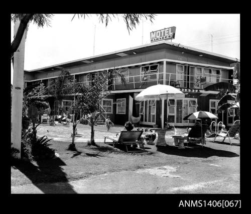 Negative depicting a two storey motel with a pool on the left and several guests using the pool area