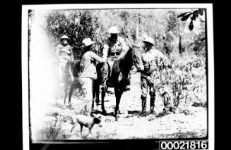 Two men on horseback talking to two men standing