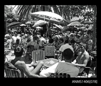 Negative depicting a resort area with guests sitting around shady tables with umbrellas