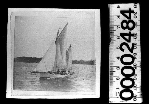 Ketch under sail on Sydney Harbour, featuring a burgee with a white cross on a dark background