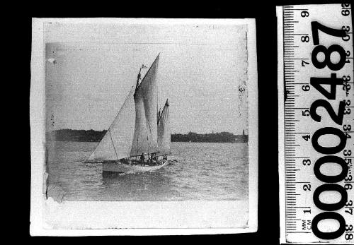 Ketch on Sydney Harbour displaying a burgee of a white cross on a dark background at mast head of mainmast