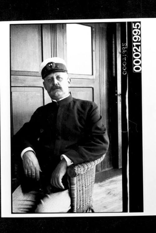 Merchant mariner sitting in wicker chair in saloon of vessel