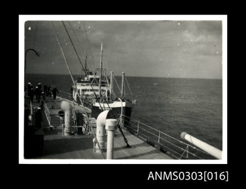 HMS KANIMBLA with sailors handling lines from an approaching cargo ship