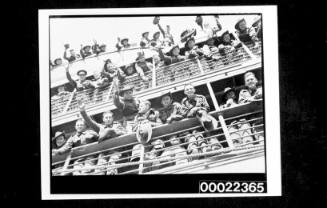 Two decks of ship with many Australian soldiers at rails, some waving