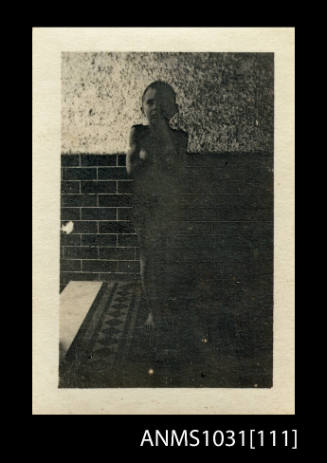 Young boy standing in front of a brick wall, and standing on a tiled floor