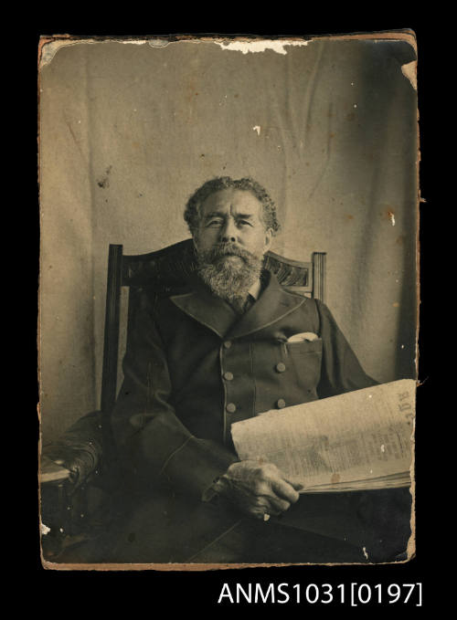 Man sitting in a chair, holding a newspaper in his hands