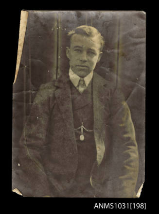 Man with his arms next to his sides, and wearing a jacket, waistcoat, shirt and tie