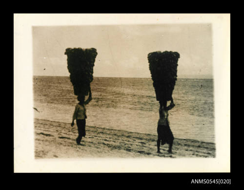 View of women carrying baskets on their heads on a beach