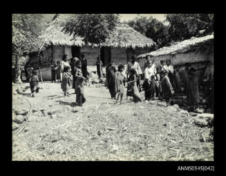 View of children standing amongst thatched huts