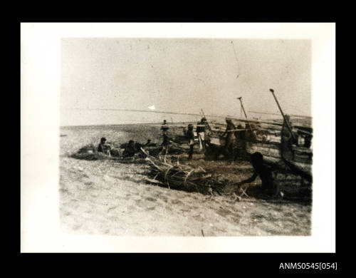 View of people and outrigger canoes on a beach