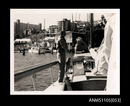 Two people standing on a yacht coming into a mooring at the CYCA