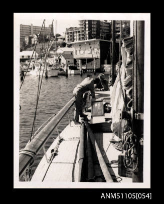 Two people standing on a yacht coming into a harbour