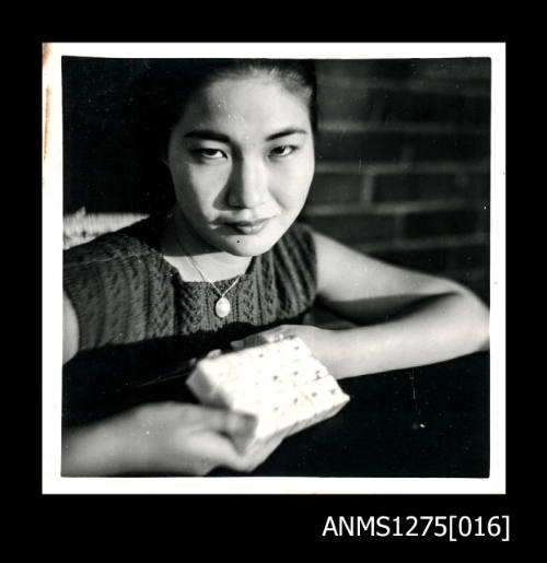 Yurie (or Yulie) George holding a container filled with padding and fifteen spherical pearls