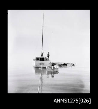 Boat called MAREA, next to smaller boat and a wooden platform, being pulled from a rope and the front of the boat