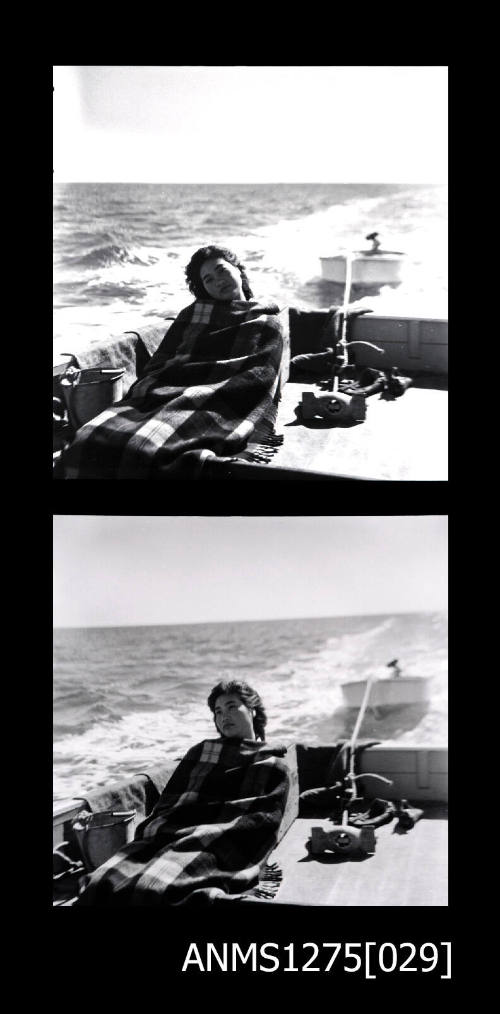 Two black-and-white negatives, joined together, both of a woman covered in a striped blanket, sitting at the back of a boat