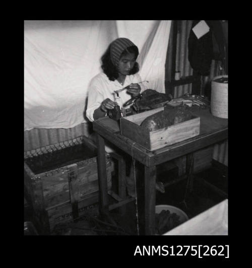 Yurie (or Yulie) George sitting at a desk seeding a pearl shell