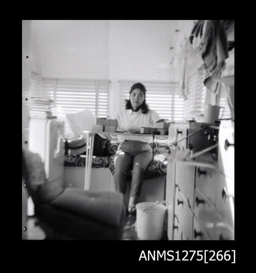 Yurie (or Yulie) George sitting on a bed, at a desk in a caravan