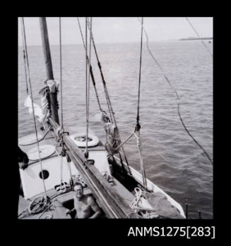 A man on a lugger, with numeruos ropes hanging around the boat