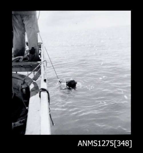 A person diving next to a boat, the helmet being visible above the water