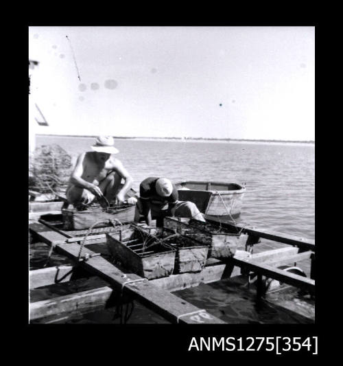 Two people working on a pearl raft with pearl cages