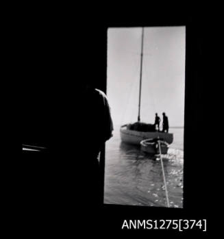 Two boats, as seen through the door of the shed, with the same woman standing next to the door