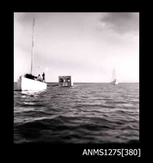 Boat pulling a pearl raft, with another boat in the distance