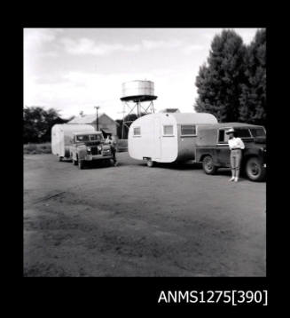 Two cars and two caravans stopped close to one another, with each driver standing beside the car